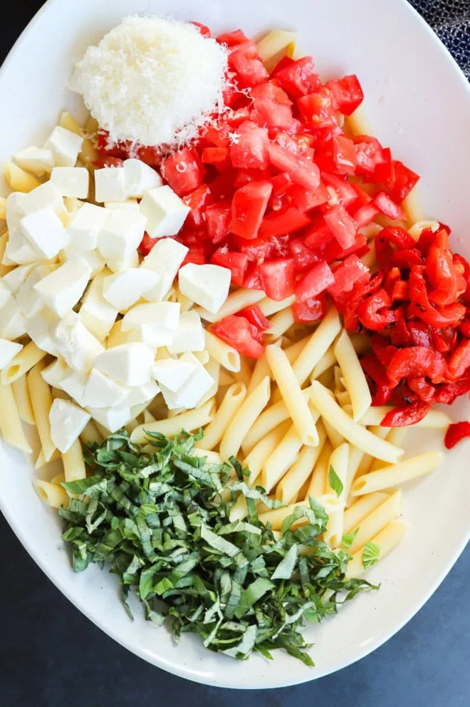 making summer lemon pasta salad in a large bowl with fresh ingredients