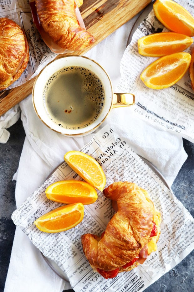 Overhead photo of breakfast sandwich with oranges and coffee