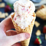 Hand holding cone of strawberry cheesecake ice cream photo