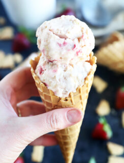 Hand holding cone of strawberry cheesecake ice cream photo