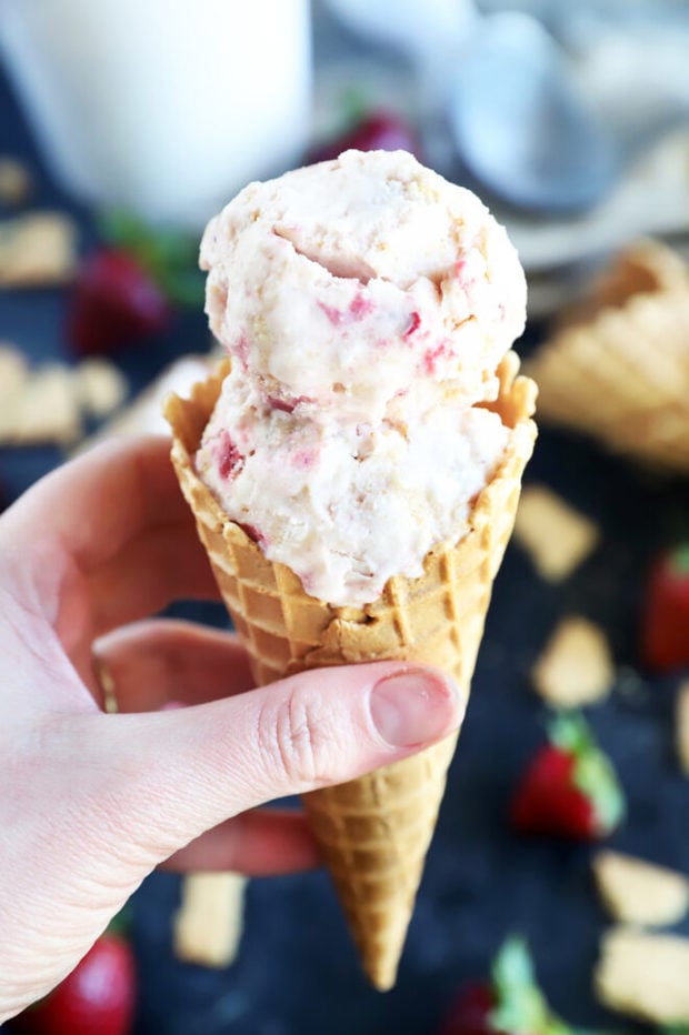 Hand holding cone of strawberry cheesecake ice cream photo