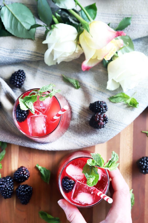 Hand holding blackberry vodka limeade cocktail