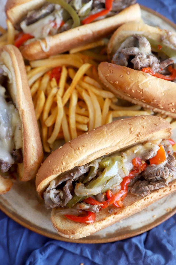 Philly cheesesteaks on plate with fries image