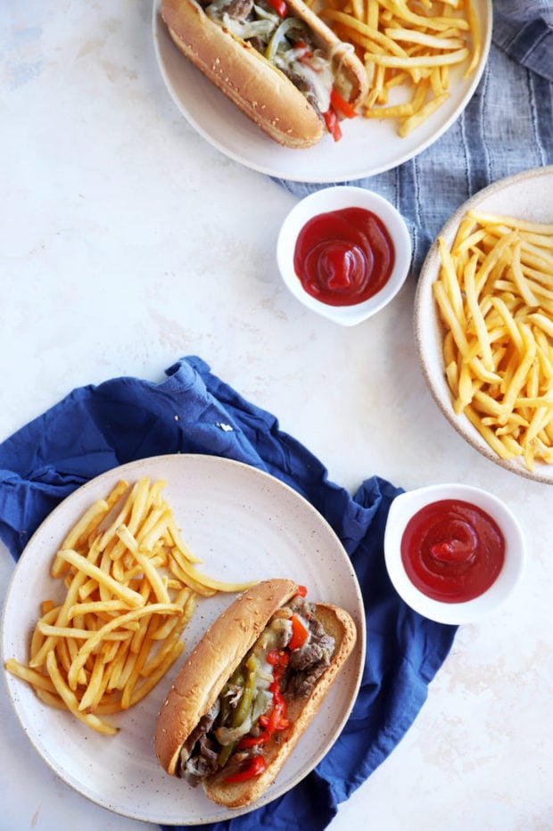 Cheesesteaks and fries on plates image