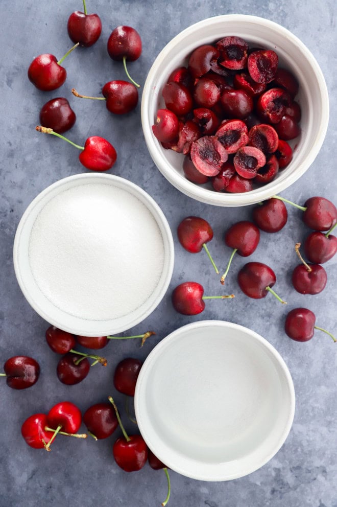 cherries in a bowl, sugar in a bowl, and water in a bowl plus fresh cherries