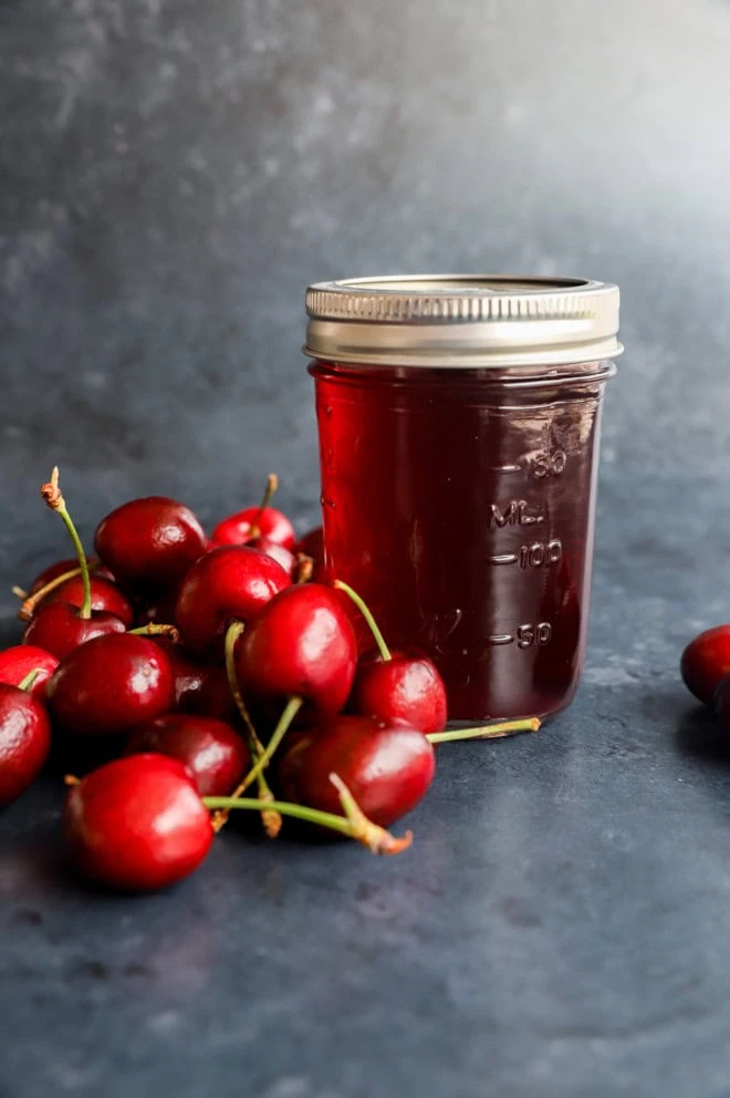 cherry simple syrup in a jar with fresh cherries