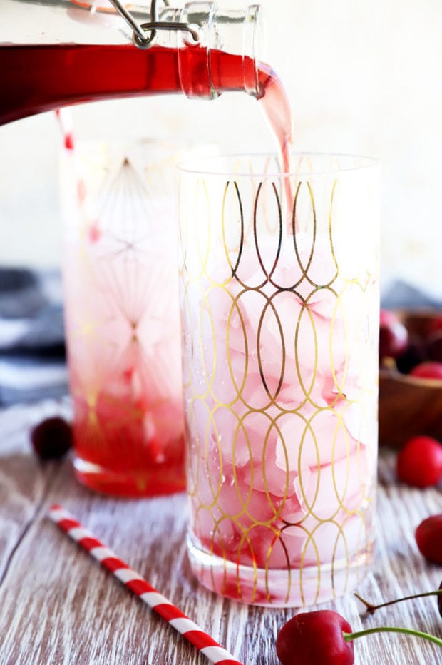 Pouring cherry simple syrup into a glass image