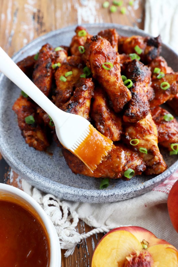 Brushing wings with peach BBQ sauce
