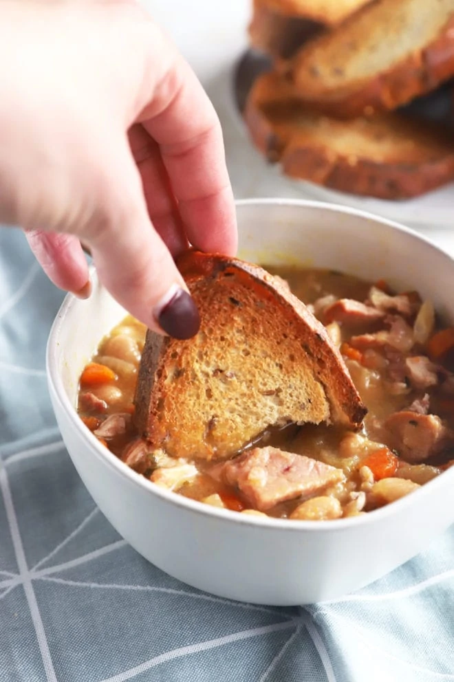 Hand dipping bread in soup image