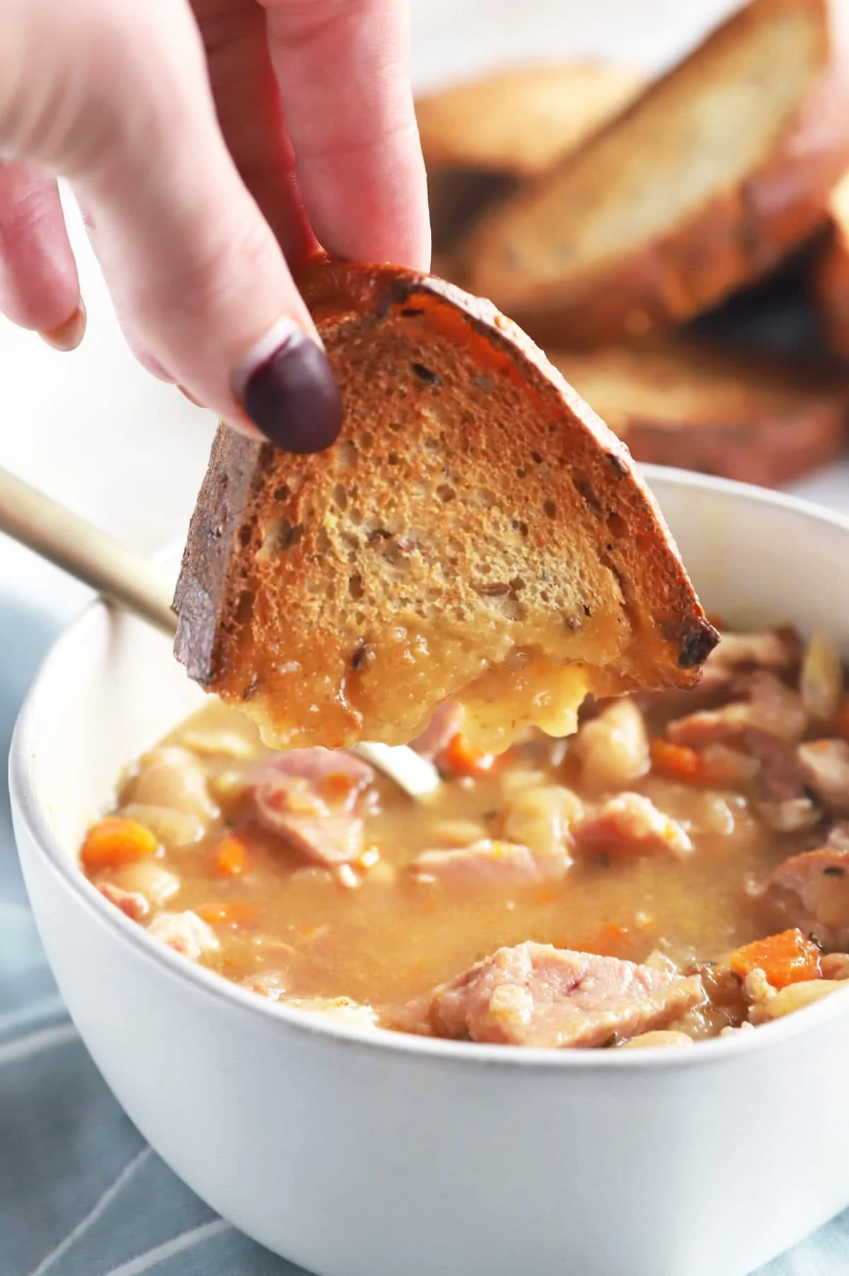 Hand dipping bread in soup image