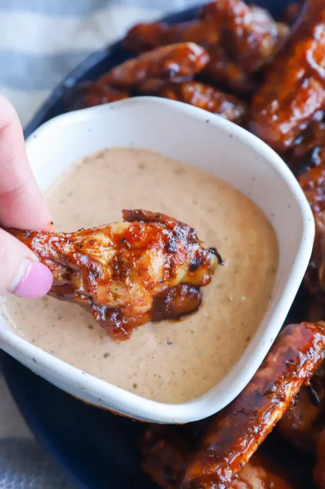 Picture of dipping a grilled chicken wing in sauce
