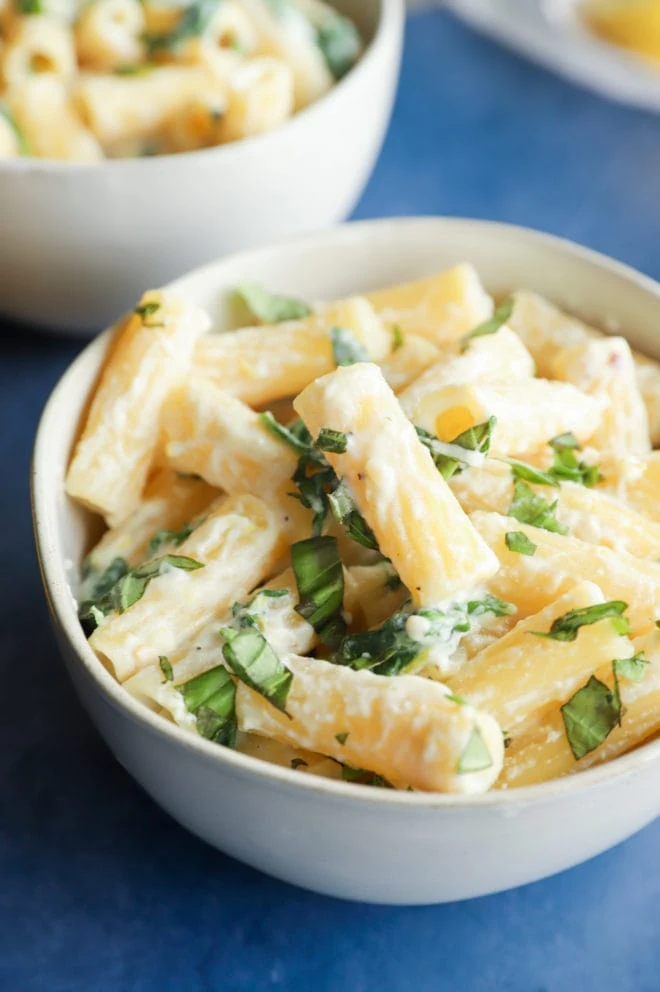 Side photo of pasta in bowl with cheese and arugula