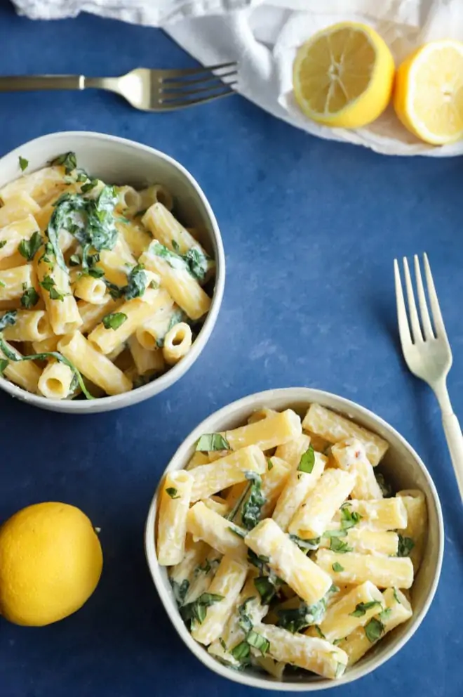 Overhead image of pasta in bowls with lemon and arugula