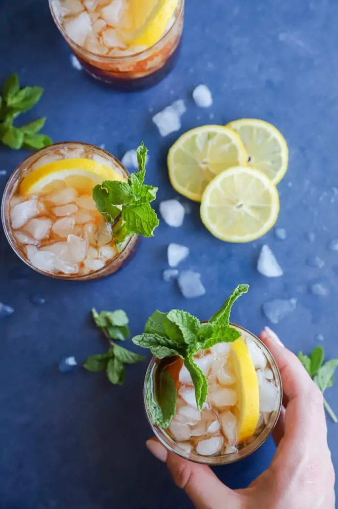 Hand holding a glass of mint tea cocktail