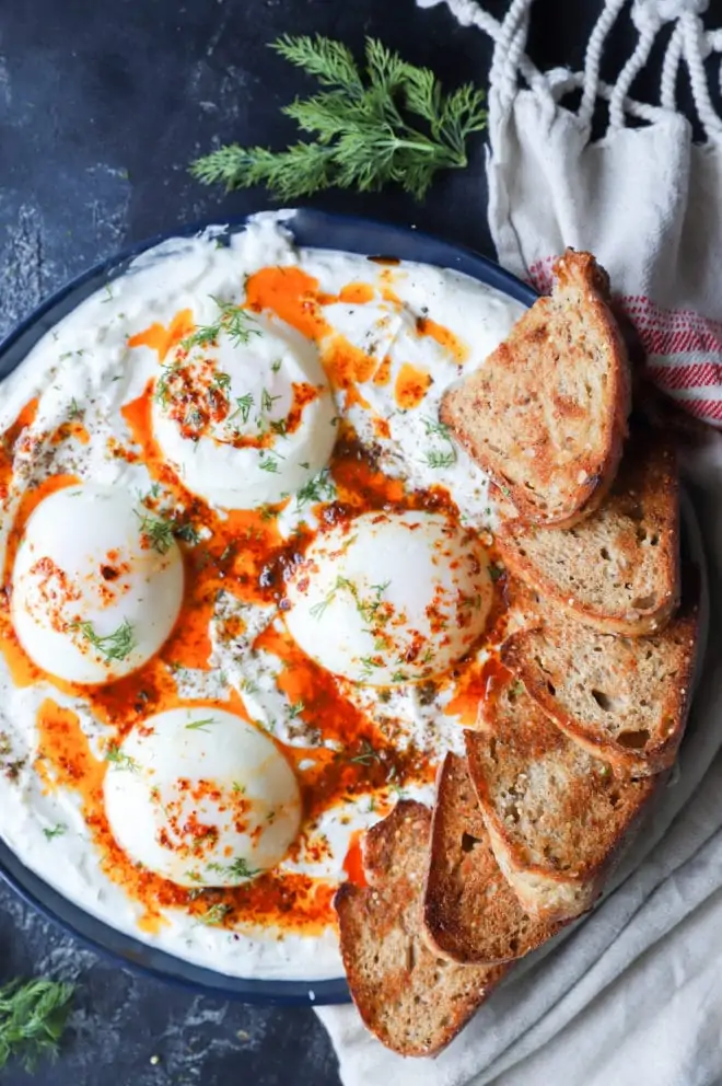 Overhead image of poached eggs platter with yogurt and butter
