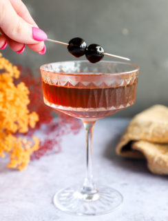 Adding a cherry garnish to a coupe glass