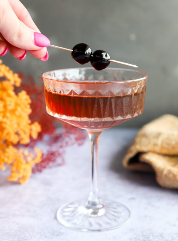 Adding a cherry garnish to a coupe glass