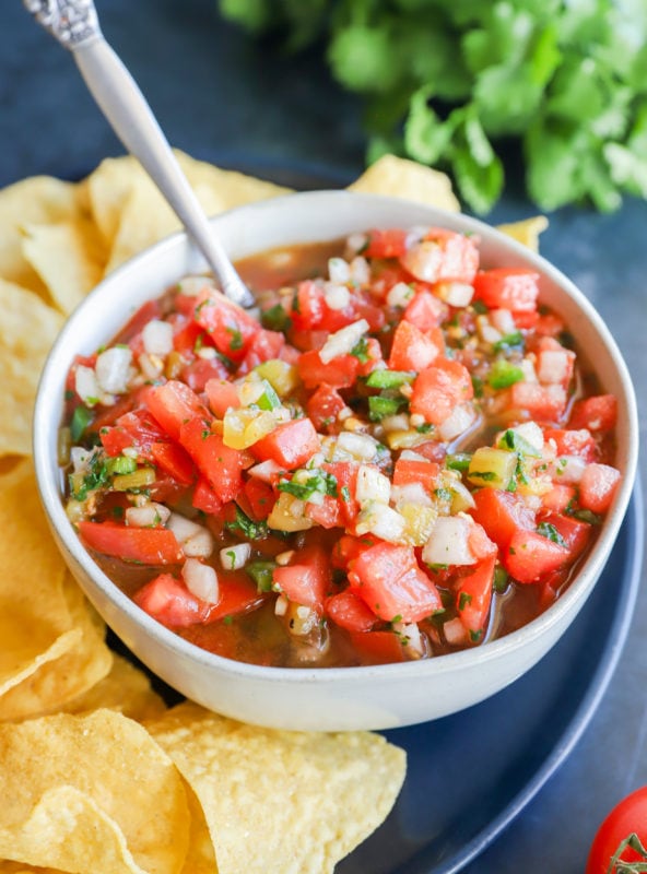 Spoon in bowl of salsa with chips