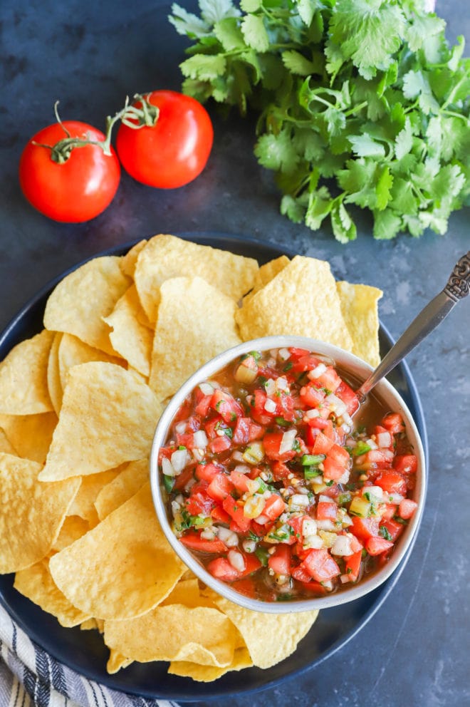 Overhead image of salsa in a bowl with chips and tomatoes
