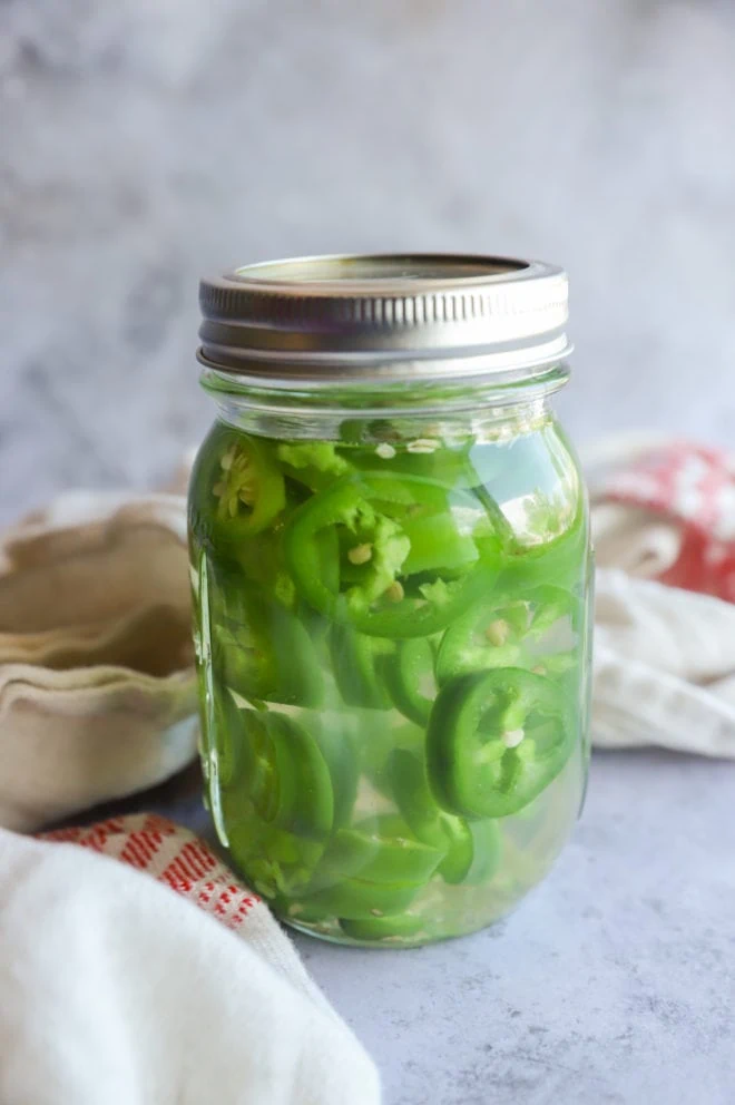 Jalapenos and serranos in mezcal in jar