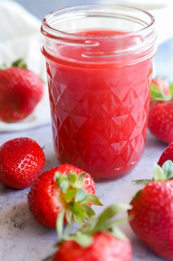 Strawberry coulis in a mason jar with strawberries