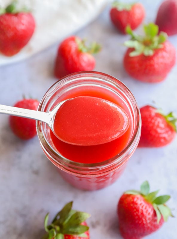 Strawberry coulis on a spoon with strawberries