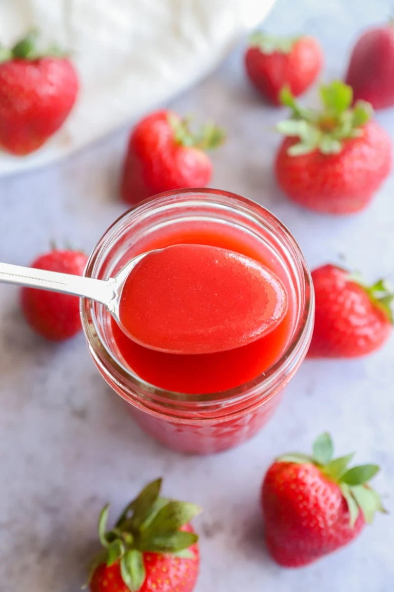 Strawberry coulis on a spoon with strawberries