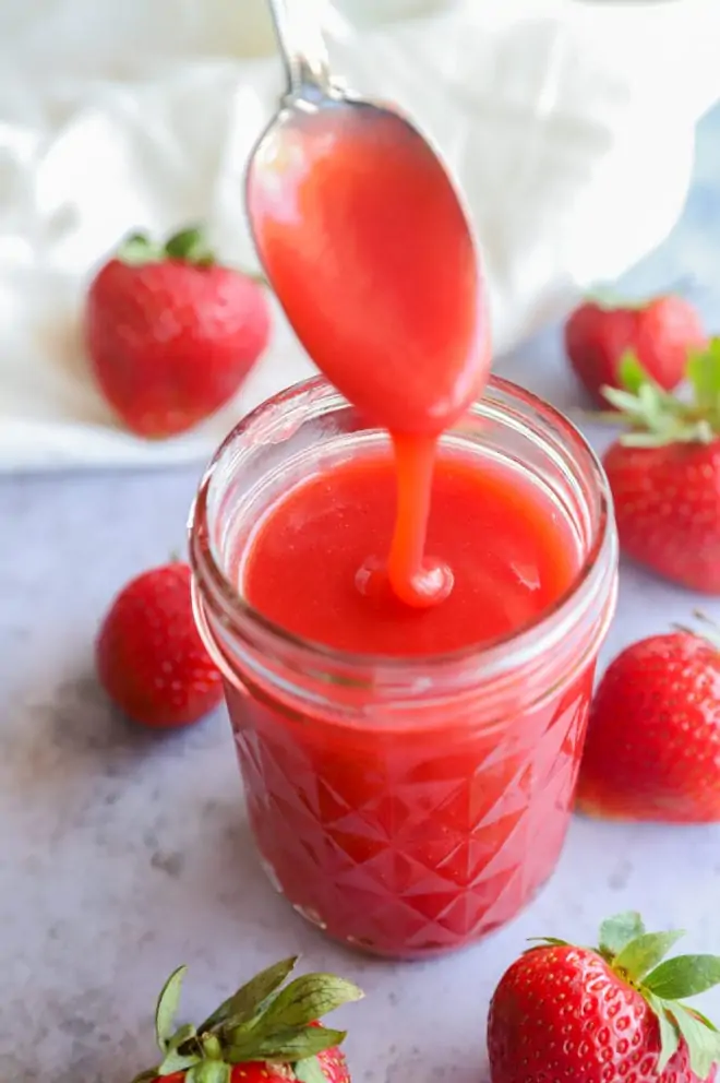 Spoon pouring in sauce for strawberries