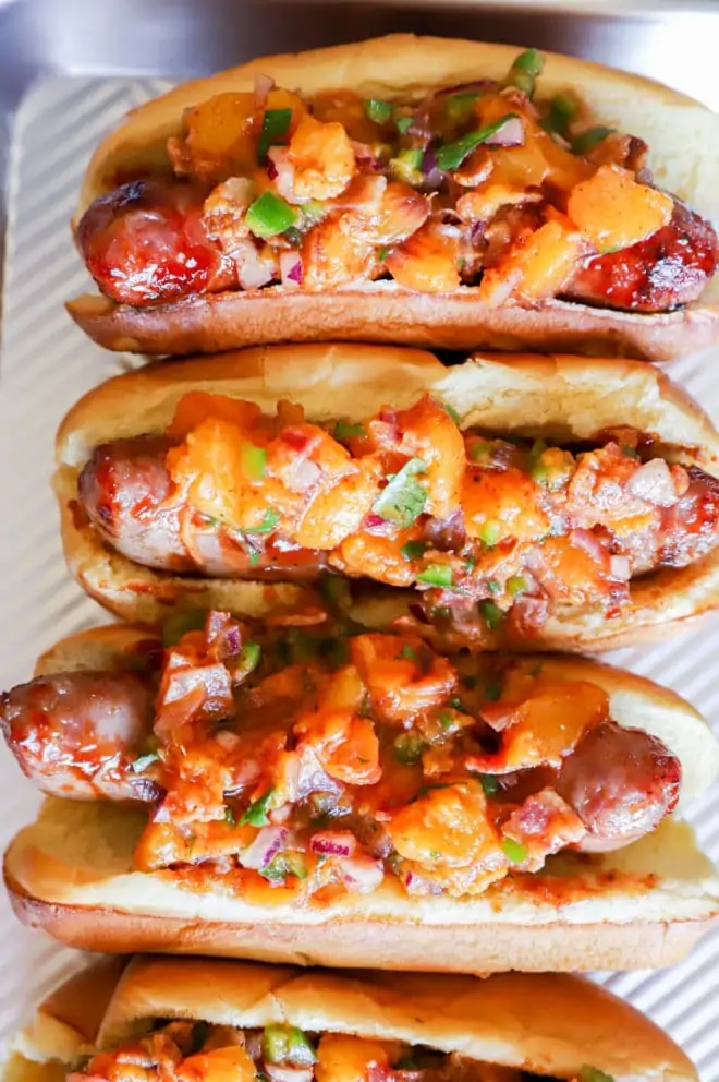 Overhead image of brats with peach salsa on top