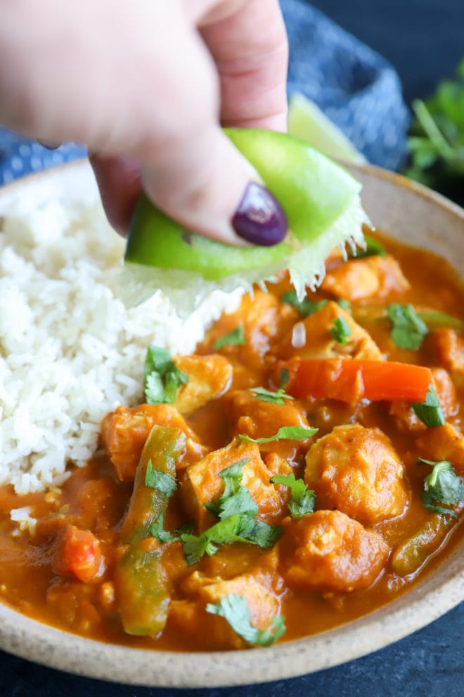 Squeezing lime over a bowl of curry and rice