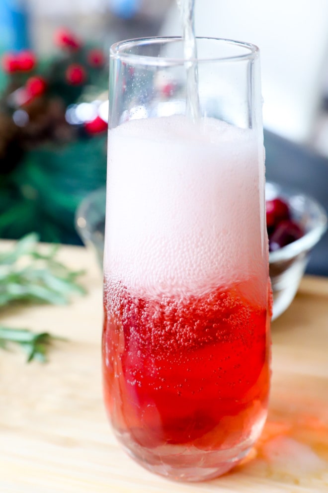 Adding champagne to a champagne flute with cranberry juice image