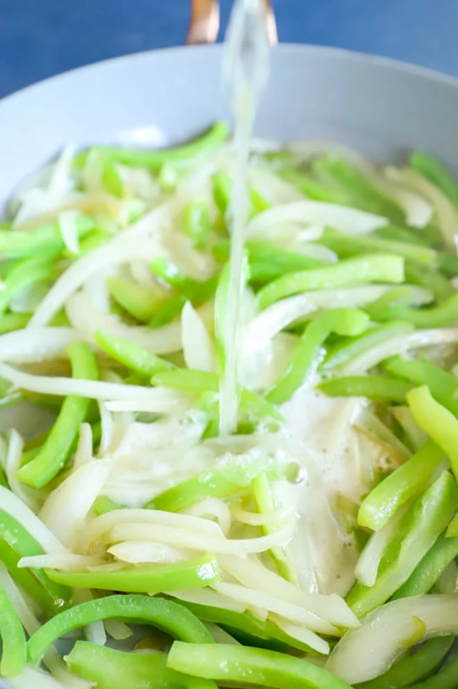 Beer being poured on vegetables in pan image