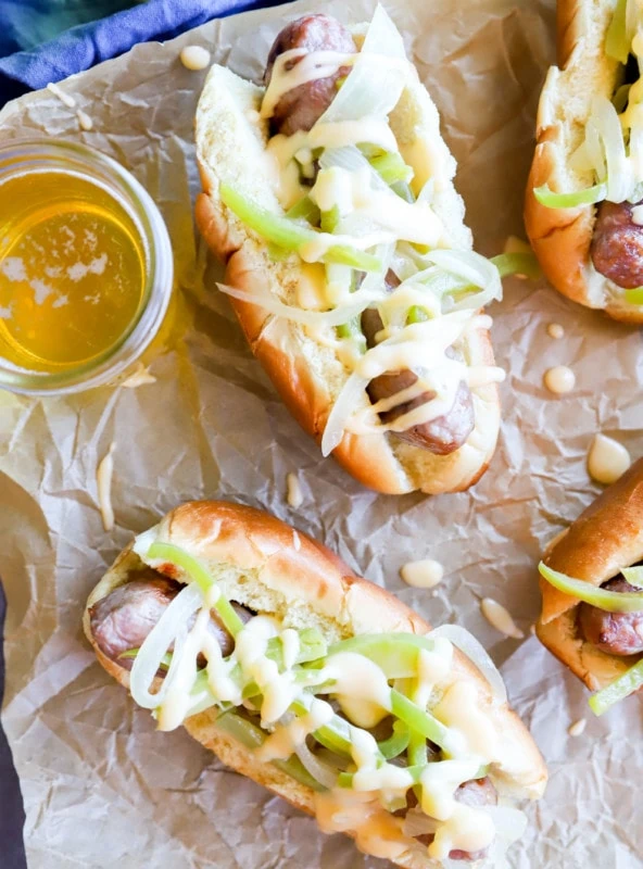 Overhead image of brats with cheese sauce