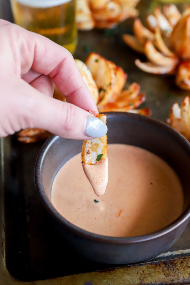 Dipping a piece of grilled onion into a dipping sauce