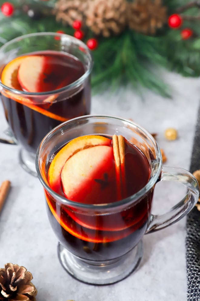 Whole spices, apple, and orange with red wine in mugs