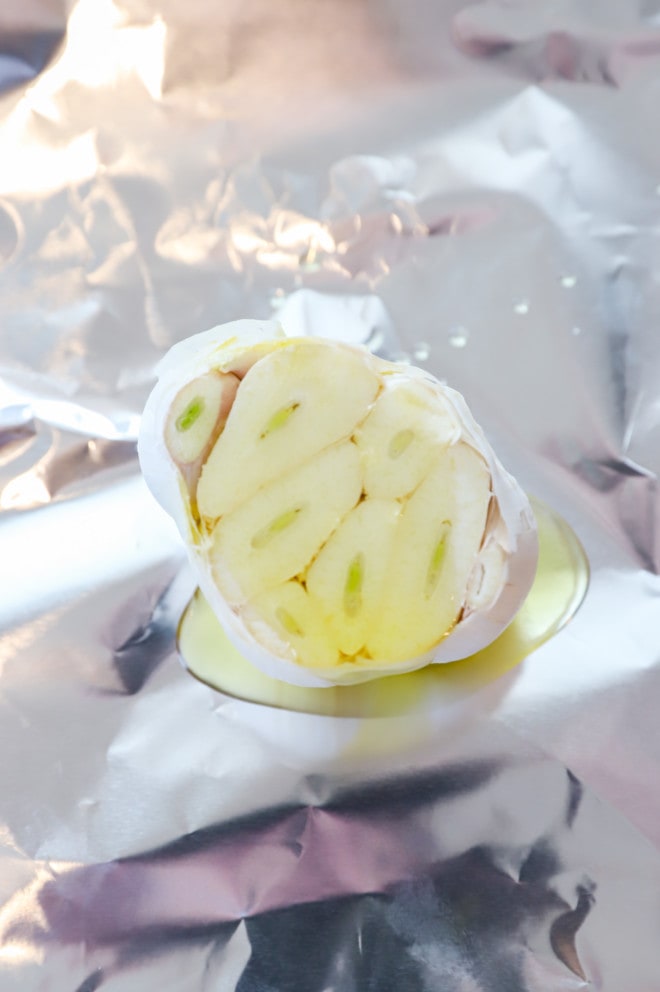 Garlic bulb drizzled with oil on foil