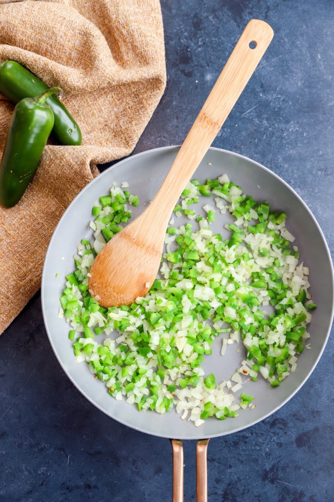 Overhead image of jalapeno and onion cooking in a skillet