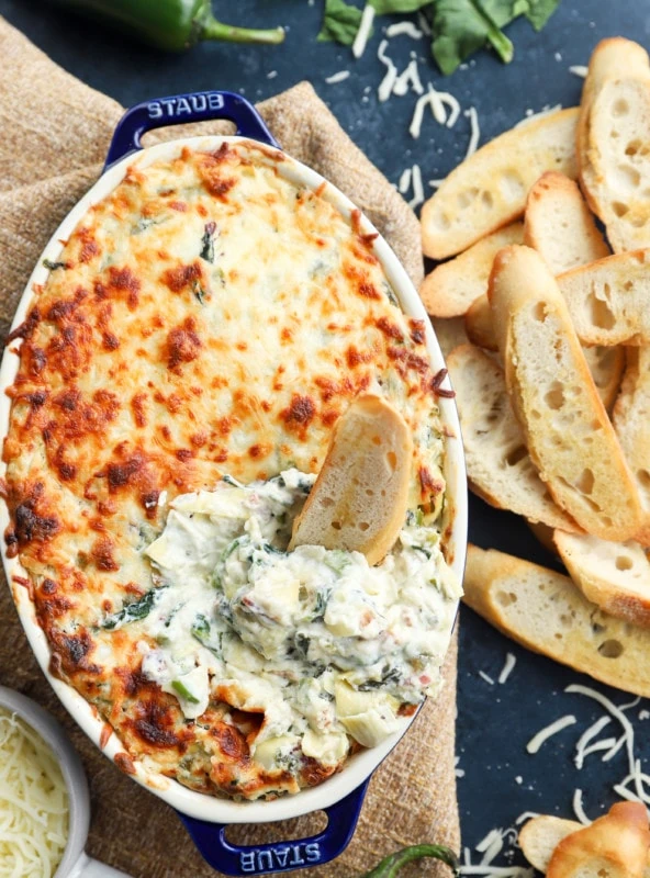 Bread dipped in creamy baked dip in baking dish