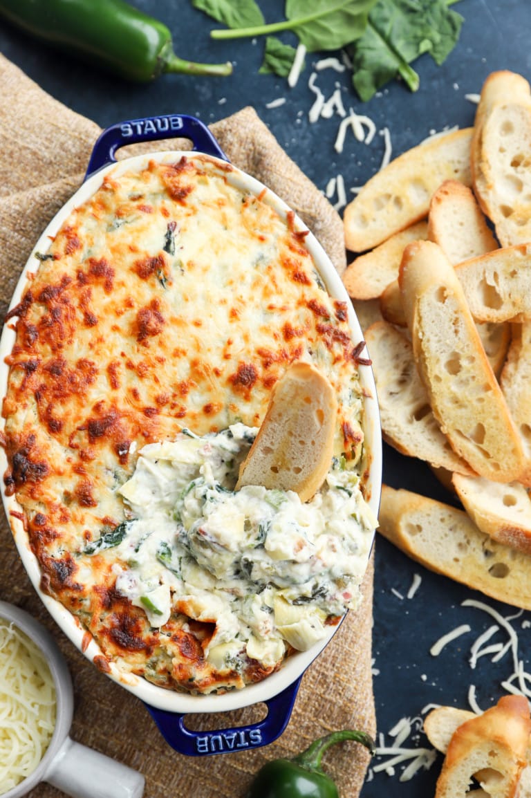 Bread dipped in creamy baked dip in baking dish