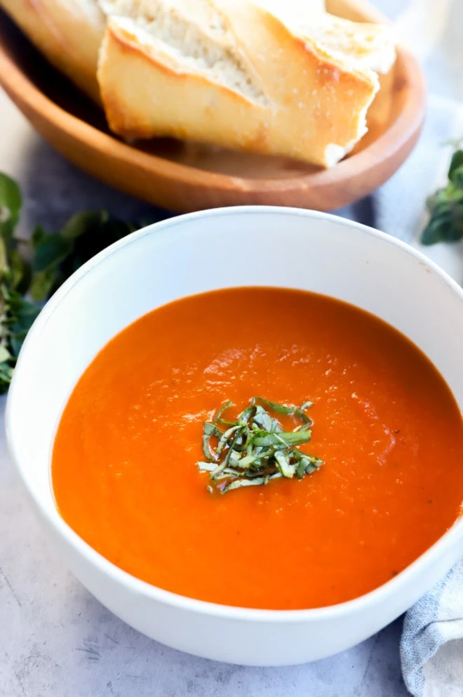 Bowl of tomato soup with basil and bread image