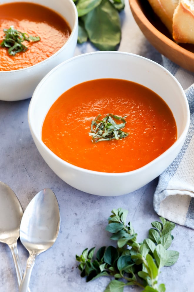 Side photo of bowls of soup with spoons and bread