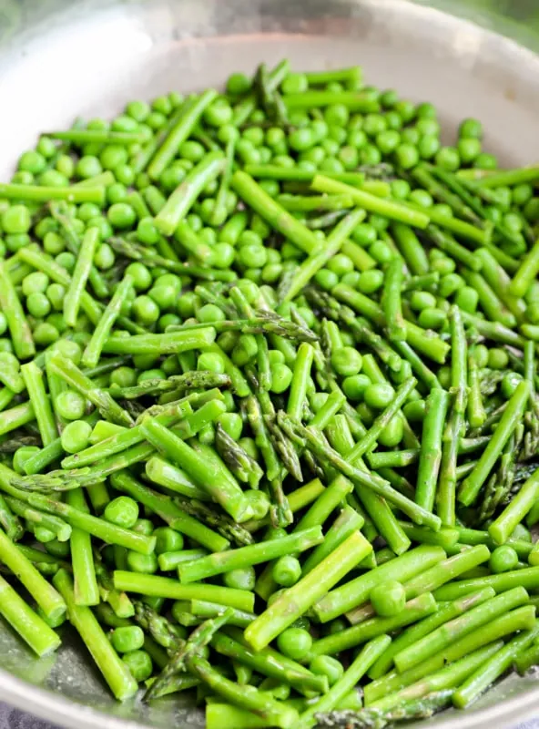 Peas and asparagus cooking in a skillet