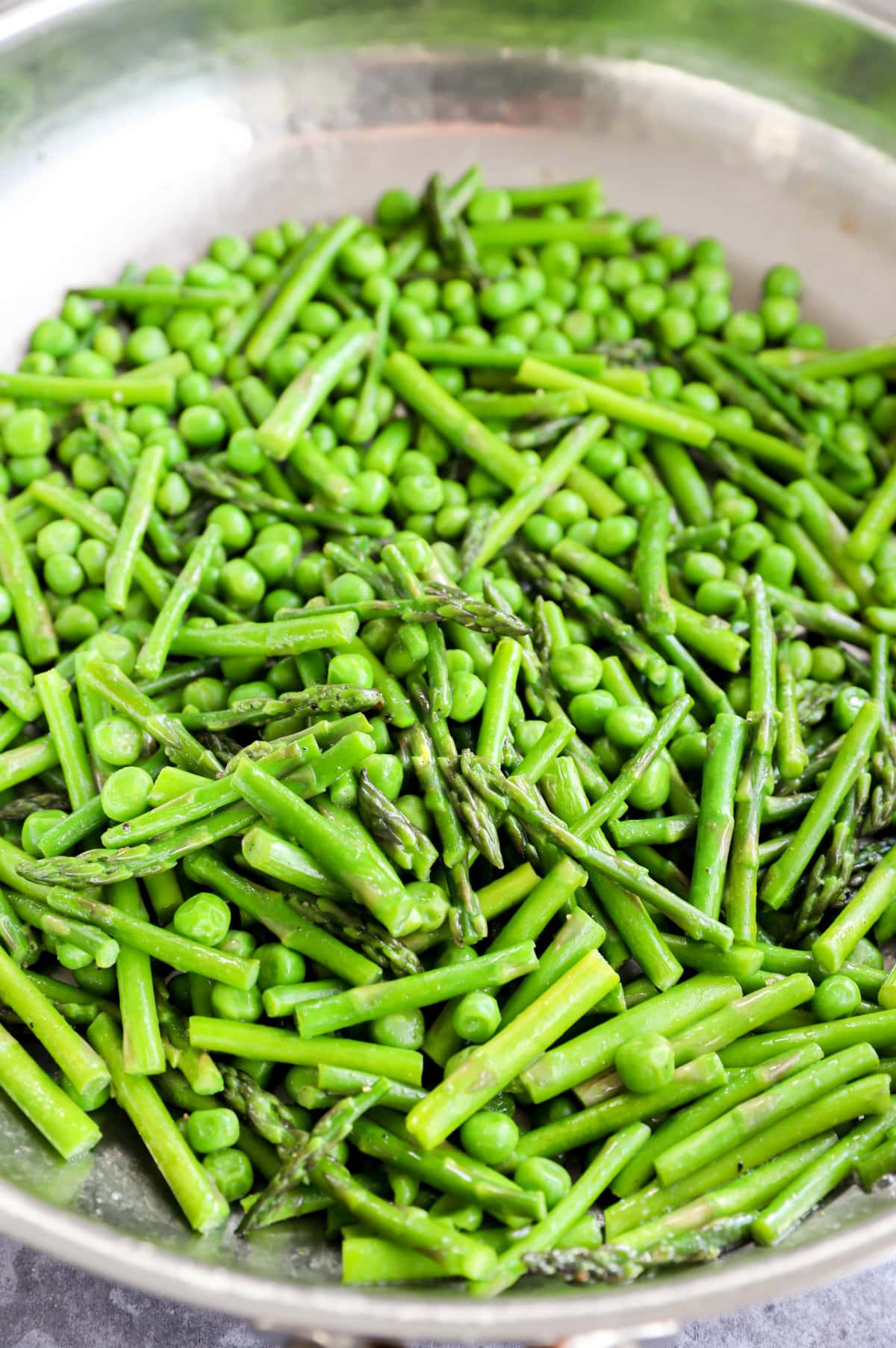 Peas and asparagus cooking in a skillet