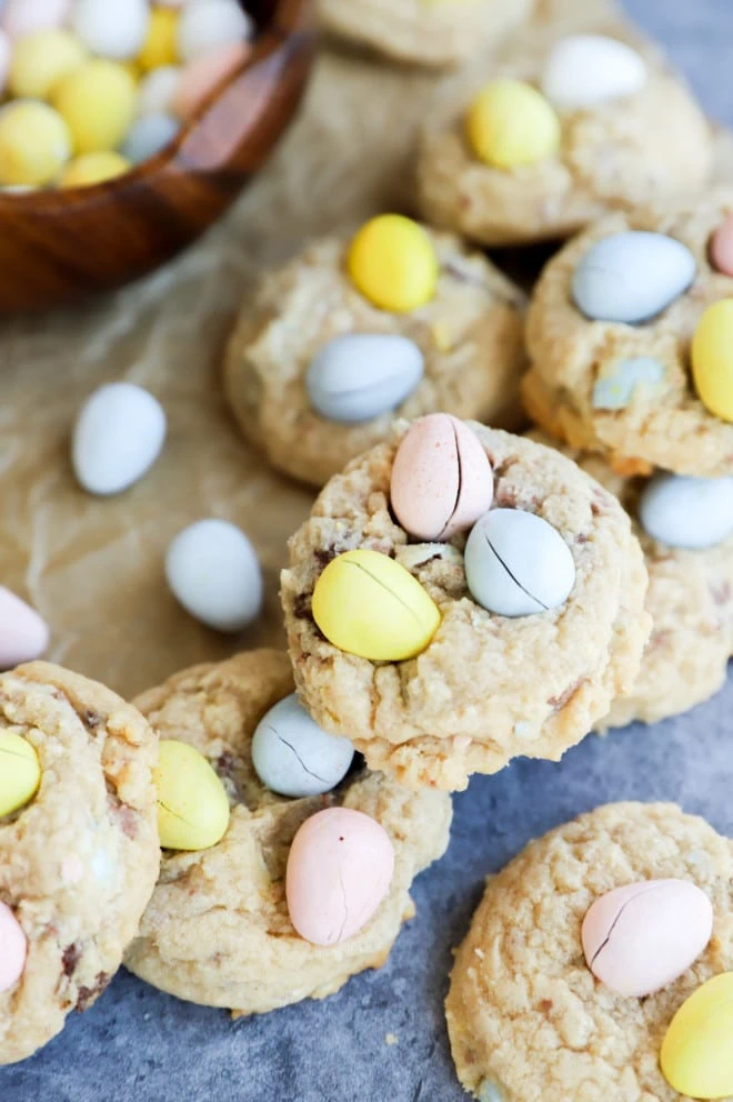 Stack of mini eggs cookies on parchment paper with eggs