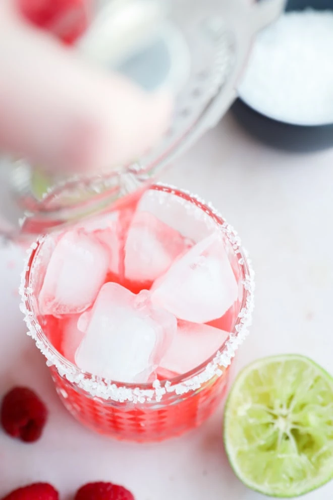 Pouring in cocktail with raspberries into cocktail glass image