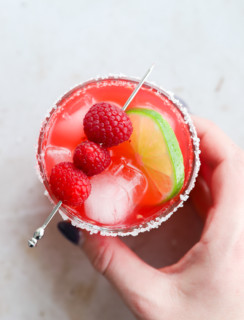 Hand holding a raspberry margarita in a glass image