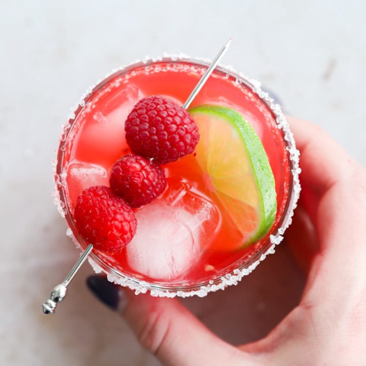 Hand holding a raspberry margarita in a glass image