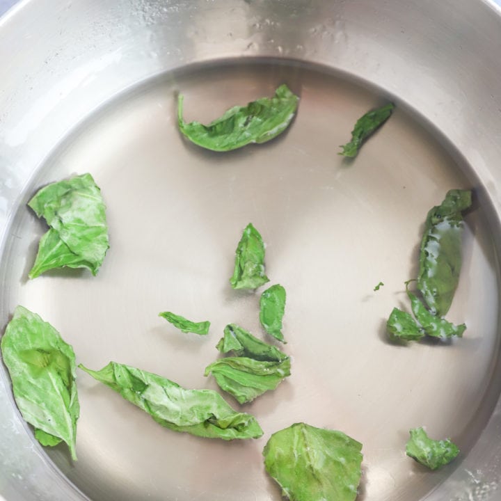 Overhead image of basil leaves in water and sugar mixture