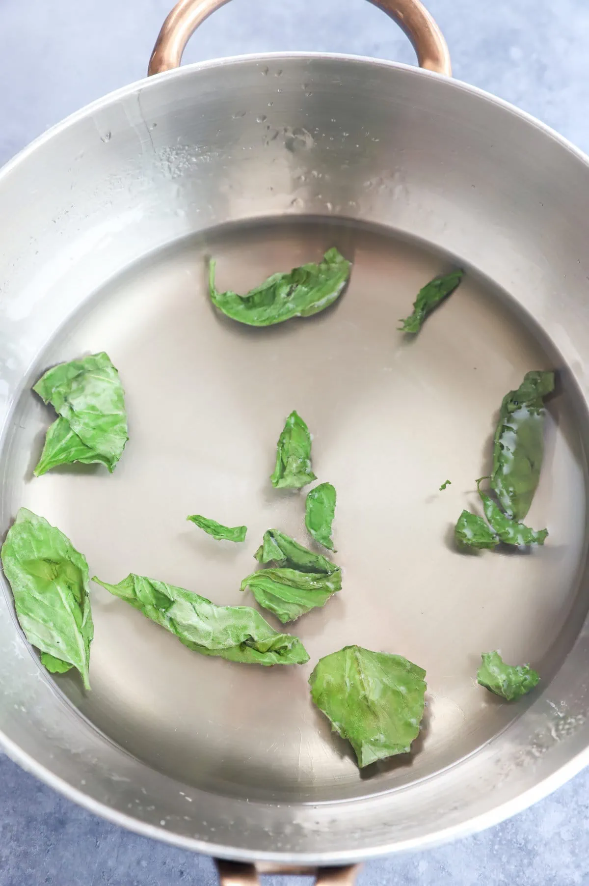 Overhead image of basil leaves in water and sugar mixture