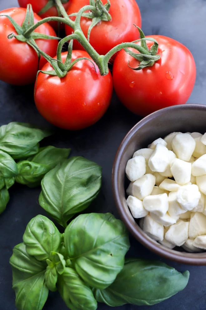 Image of tomatoes, mozzarella, and basil on table